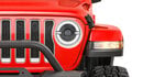 The front grille and headlight of a red Jeep Wrangler