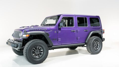 Purple four-door Jeep Wrangler with a white background.