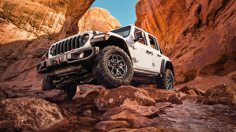 White Jeep Wrangler climbing over rocks 
